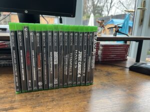 Row of Xbox One game cases lined up spine-out on a desk, including Guardians of the Galaxy, Jusant, Halo 5 and Titanfall 2