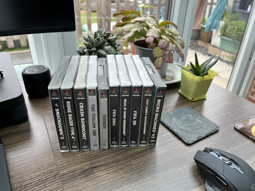 physical media still matters A flat overhead view of a stacked pile of original PlayStation 1 video game cases.