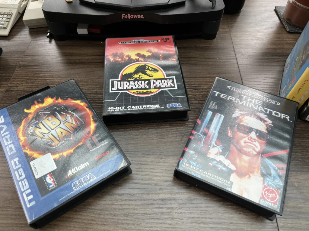 Two retro Sega Mega Drive game cartridges side-by-side, featuring Jurassic Park and The Terminator.